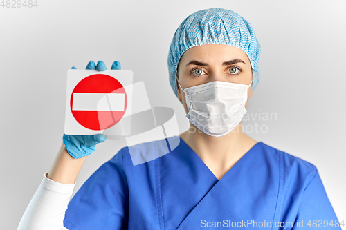 Image of doctor or nurse in face mask showing stop sign