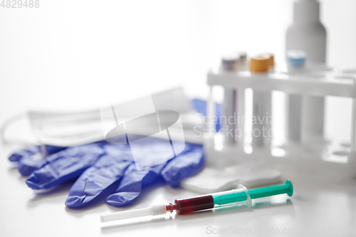 Image of close up of blood in syringe, gloves and mask