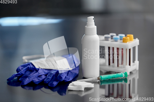 Image of syringe, beakers with blood test, gloves and mask