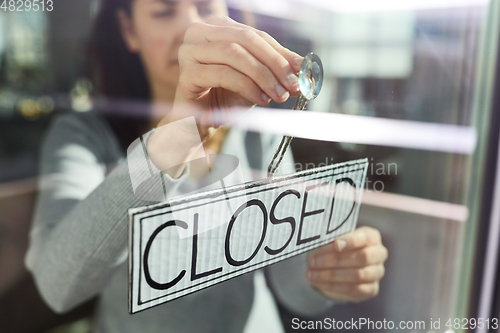 Image of woman hanging banner with closed word on door