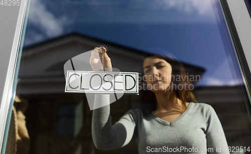 Image of woman hanging banner with closed word on door