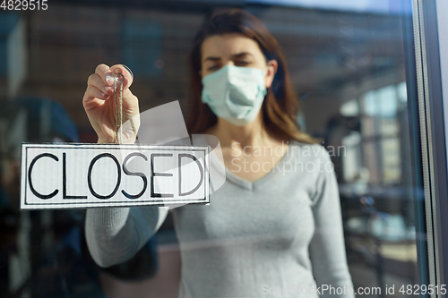 Image of woman in mask hanging banner closed on door