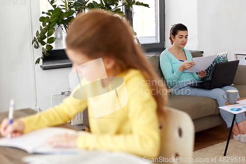 Image of mother working and daughter studying at home