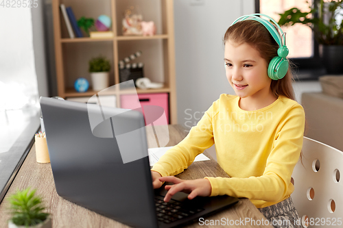 Image of girl in headphones with laptop computer at home