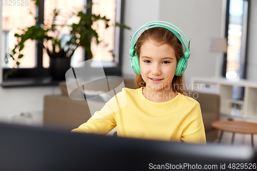 Image of girl in headphones with laptop computer at home