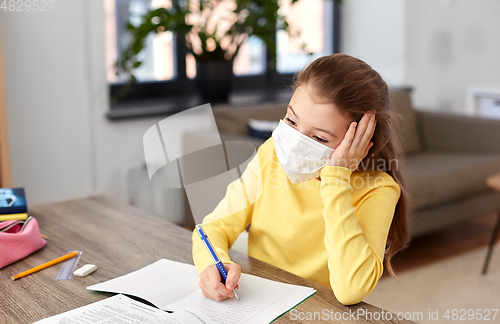 Image of bored sick girl in medical mask learning at home