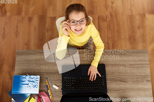 Image of smiling student girl typing on laptop at home