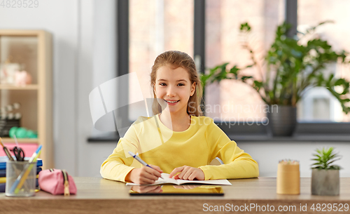 Image of student girl writing to notebook at home