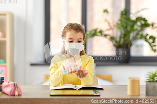 Image of sick girl in mask with hand sanitizer at home