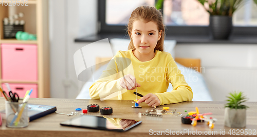 Image of happy girl playing with robotics kit at home