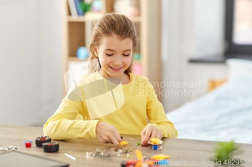 Image of happy girl playing with robotics kit at home