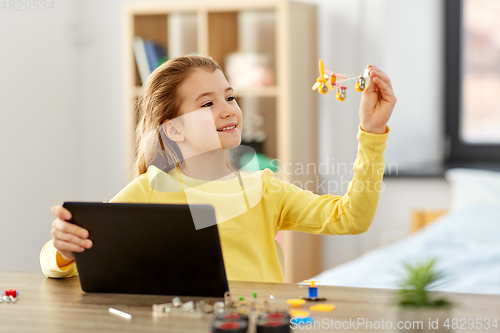 Image of girl with tablet pc and robotics kit at home