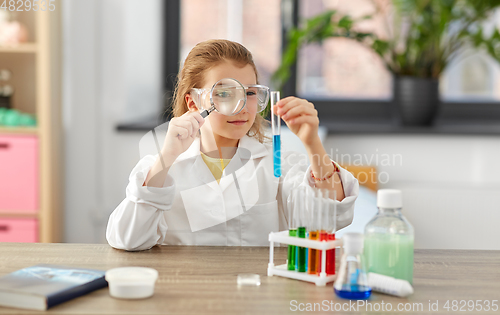 Image of girl with magnifier and beaker at home laboratory