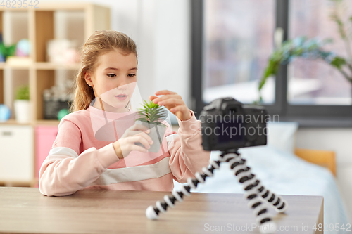 Image of girl with camera and flower video blogging at home