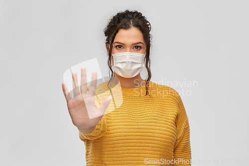 Image of woman in medical mask making stop gesture