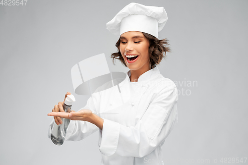 Image of female chef with hand sanitizer or liquid soap