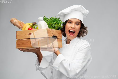 Image of happy smiling female chef with food in wooden box