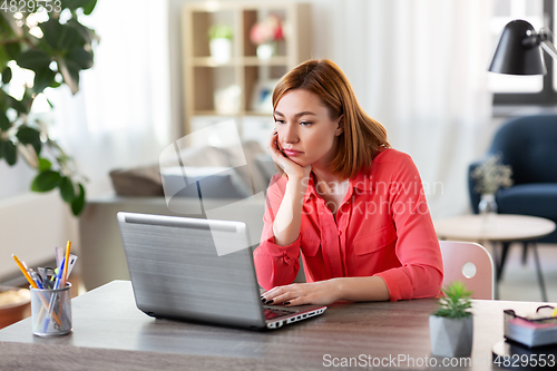 Image of bored woman with laptop working at home office