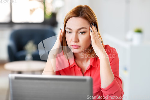 Image of stressed woman with laptop working at home office