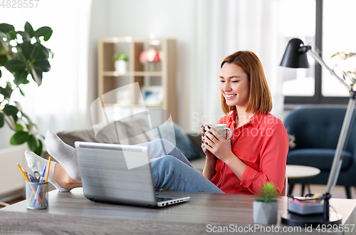 Image of woman with laptop drinking coffee at home office