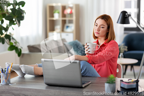 Image of woman with laptop drinking coffee at home office