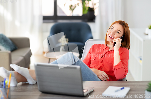 Image of smiling woman calling on smartphone at home office
