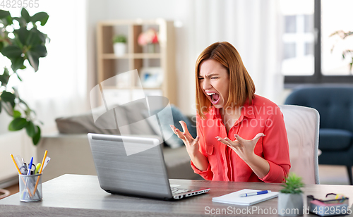 Image of angry woman with laptop working at home office