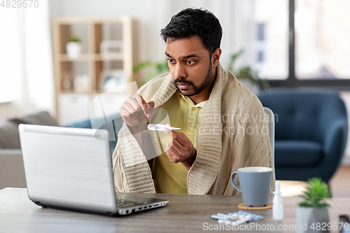 Image of sick man thermometer having video call on laptop