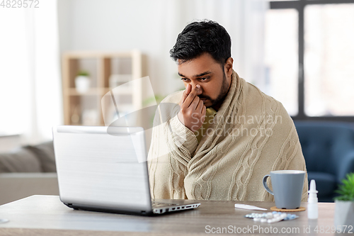 Image of sick indian man having video call on laptop