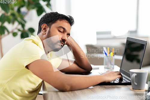 Image of indian man sleeping on table with laptop at home