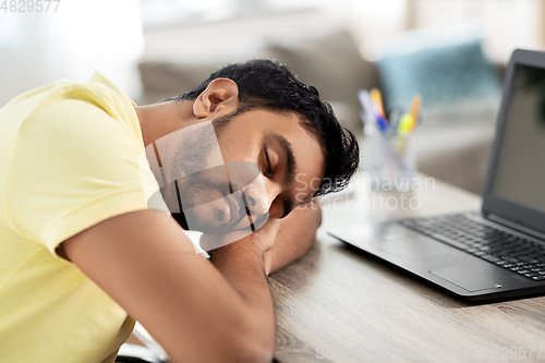 Image of indian man sleeping on table with laptop at home