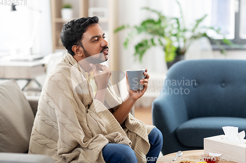 Image of sick man with tea touching his sore throat at home