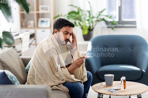 Image of sick man measuring temperature by thermometer