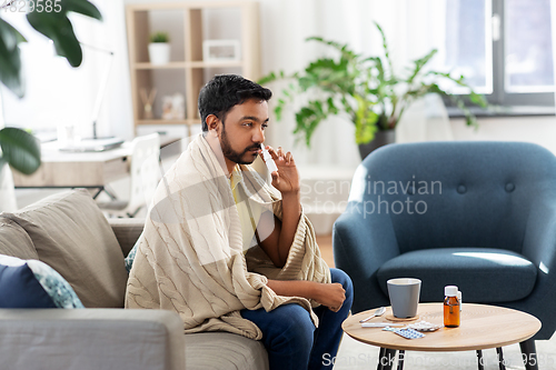 Image of sick indian man using nasal spray at home