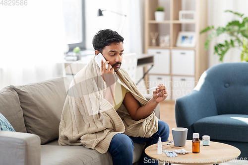 Image of sick man with thermometer calling on smartphone