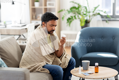 Image of sad sick man in blanket with medicine at home