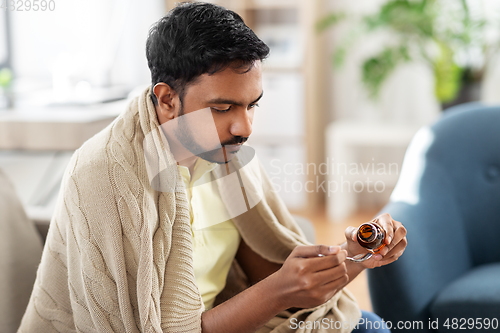 Image of sick man pouring medication from bottle to spoon