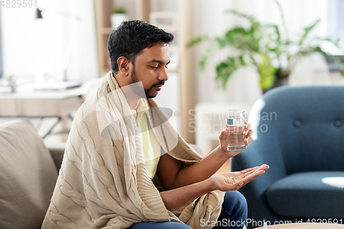 Image of sick man with medicine and glass of water at home