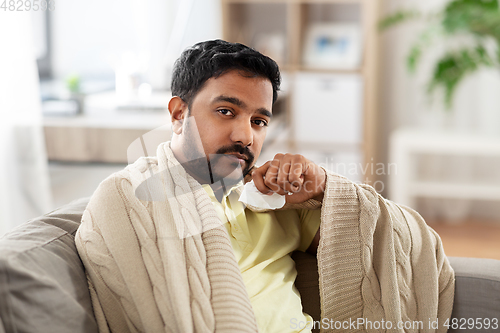 Image of sick man in blanket with paper tissue at home