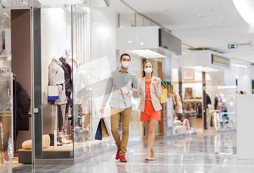 Image of couple in medical masks with shopping bags in mall