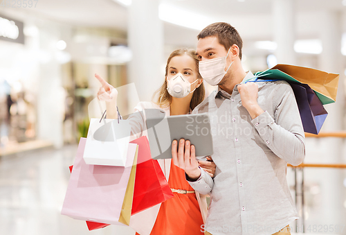 Image of couple in masks with tablet pc in shopping mall