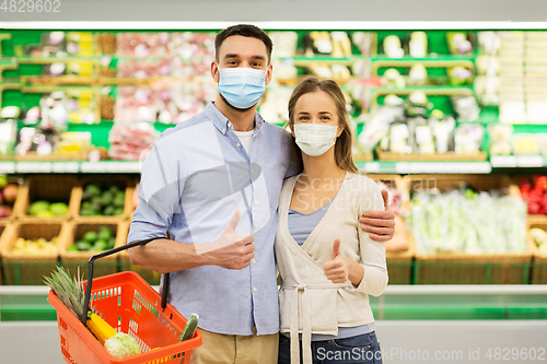 Image of couple in masks with food basket at grocery store