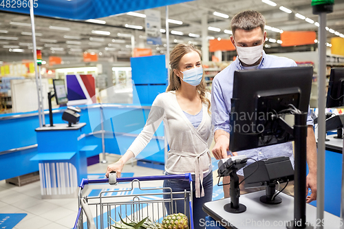 Image of couple in masks buying food at store cash register