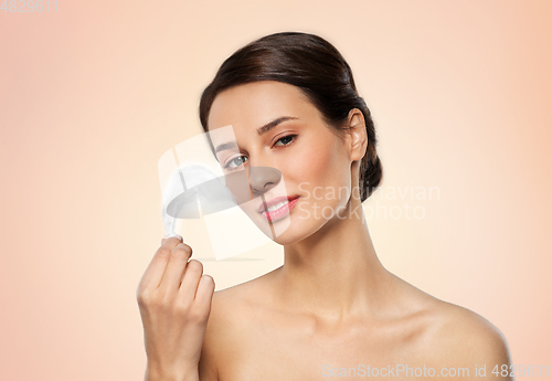 Image of beautiful woman with feather touching her face