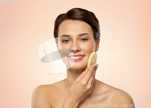 Image of young woman cleaning face with exfoliating sponge