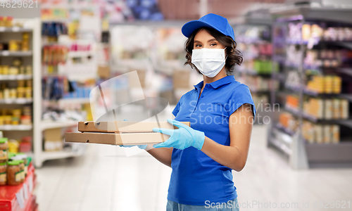 Image of delivery woman in mask with pizza boxes at store