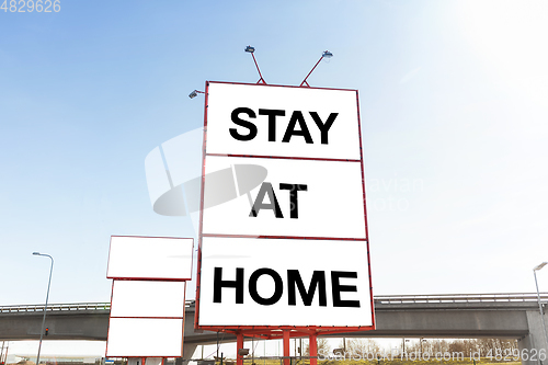 Image of big billboard with stay at home words in city
