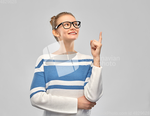 Image of happy teenage girl in glasses pointing finger up