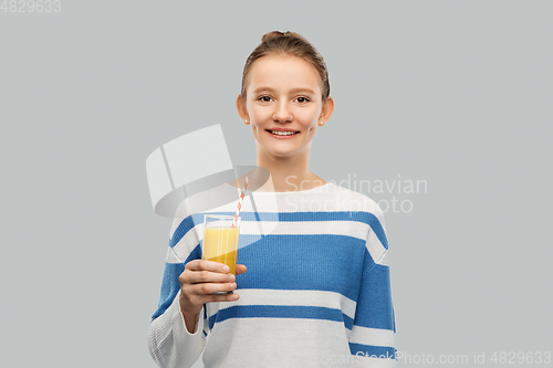 Image of smiling teenage girl holding glass of orange juice