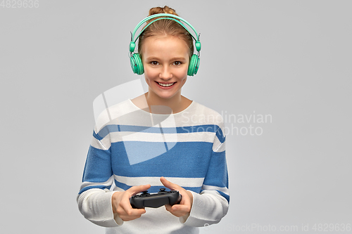 Image of happy teenage girl with gamepad playing video game